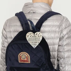Close-up of heart-shaped wooden friendship plaque hanging on a blue velvet backpack