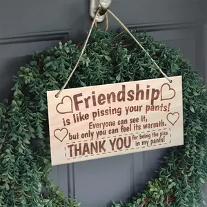 Detail of wooden hanging sign with humorous quote and jute rope on a rustic wreath