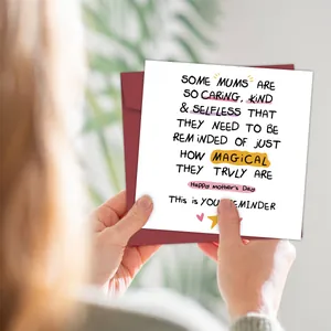 Close-up of hands holding a Mother's Day card and red envelope in a cozy home setting
