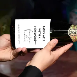 Close-up of hands holding a wine bottle with decorative new home gift stickers