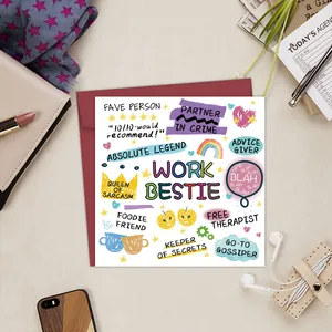 Close-up of Work Bestie square birthday card with red envelope on a busy desk
