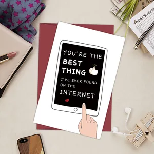 Close-up of a funny birthday card and red envelope on a tidy desk with lifestyle items