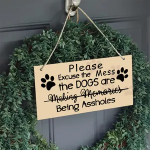 Detail of wooden dog-themed door sign hanging inside a green leaf wreath on a door