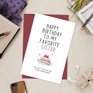 Modern flat lay of funny birthday card for sister with dark red envelope and accessories
