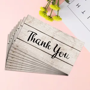 Detail view of rustic wood texture Thank You cards stacked on a soft pink background