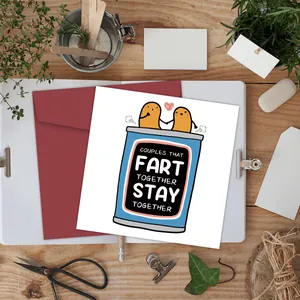 Funny flat lay of a square birthday card and red envelope on a light wooden desk