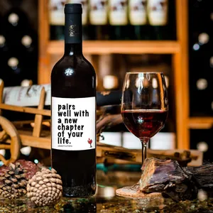 Close-up of congratulations wine label on bottle with a glass of red wine and props