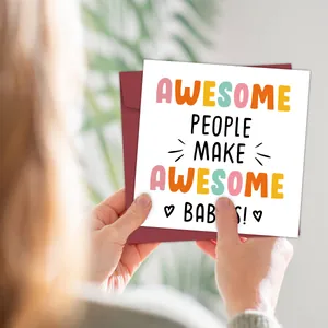 Close-up of funny baby greeting card with burgundy envelope and creative hand-held display
