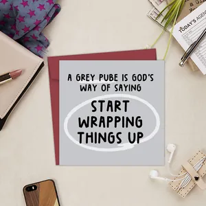 Flat lay of a funny square greeting card and red envelope among lifestyle desktop accessories