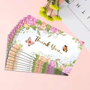 Macro shot of watercolor thank you cards with floral designs and gold geometric accents