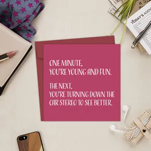Detailed view of funny pink birthday card and red envelope on a stylish desktop