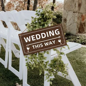 Close-up of wooden wedding sign with arrows hanging on a chair in a garden setting