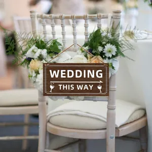 Rustic dark wood wedding directional sign with white text and arrow on floral chair