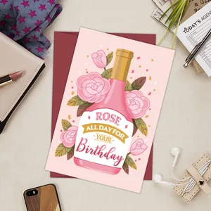 Flat lay of Rose All Day birthday card with a red envelope and lifestyle props