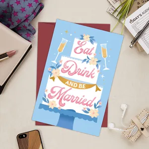 Artistic wedding greeting card with a 3-layer cake and deep red envelope on a beige desk