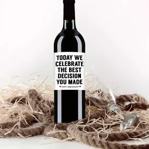 Close-up of funny anniversary wine bottle labels on black glass with heart decor