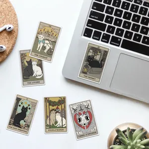 Flat lay of cat tarot stickers with waterproof coating on a laptop and desk setup