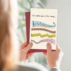 Carte de vœux musicale avec notes colorées et une enveloppe rouge foncé en main