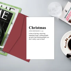Vue à plat d'une carte de Noël amusante avec enveloppe rouge sur une table basse