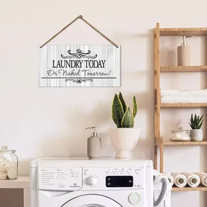 Rustic wood laundry room sign with humorous quote hanging on white wall above washer