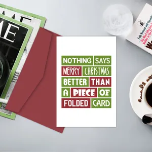 Détail d'une carte de Noël minimaliste avec texte humoristique et enveloppe rouge