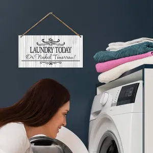 Detail of wooden laundry sign with rope hanger next to towels and washing machine