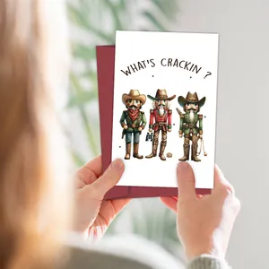 Lustige Weihnachtskarte mit Cowboy-Nussknackern und rotem Umschlag in der Hand