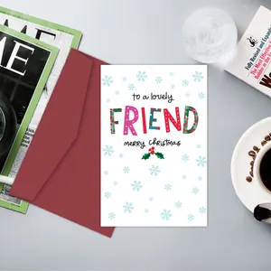 Gros plan d'une carte de Noël pour amis avec enveloppe rouge sur un bureau au style cosy