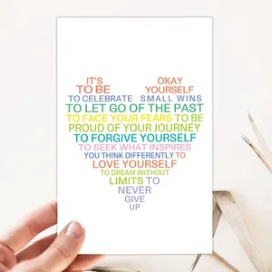 Tarjeta de felicitación con forma de corazón y citas motivacionales sobre papel blanco