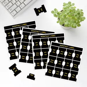 Autocollants d'index mensuels noir et or sur un bureau avec un carnet de notes