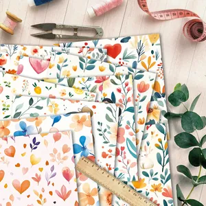 Draufsicht auf Aquarell-Scrapbook-Papier mit Blumenmotiven und Bastelwerkzeug auf Holz