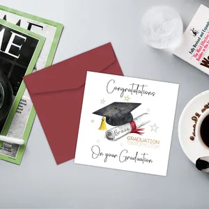 Dettaglio del biglietto di laurea con tocco nero ed elegante busta rossa su scrivania