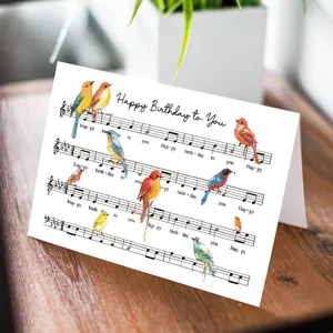Detail van verjaardagskaart met kleurrijke vogels en muzieknoten op houten tafel