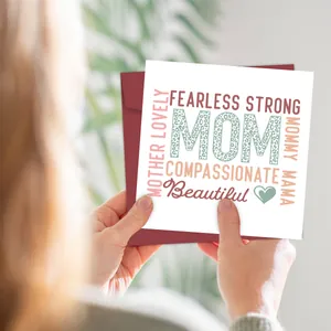 Detailed view of a square Mother's Day card with a red envelope held by a person