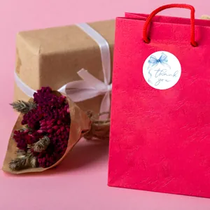 Detail of pink Thank You sticker with blue bow on gift bag for packaging