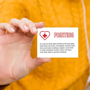Macro view of first aid card for fainting instructions held against yellow background