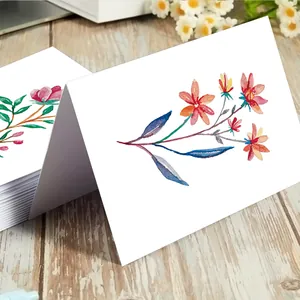 Detail shot of watercolor floral cards on wooden table with elegant white flowers