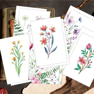 Detailed close-up of watercolor floral greeting cards on vintage book background