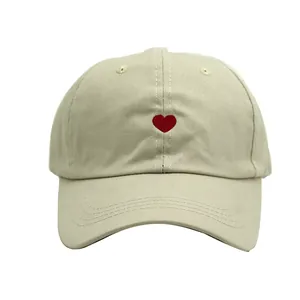 Gros plan détaillé d'une broderie de petit cœur rouge sur une casquette de baseball beige