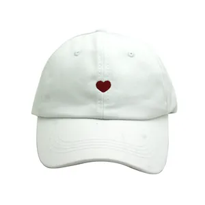 Détail de la broderie cœur rouge sur le devant d'une casquette de baseball blanche
