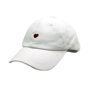 Détail rapproché de la broderie cœur rouge sur une casquette de baseball en coton blanc