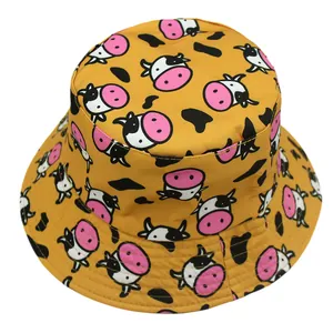 Reversible bucket hat in deep yellow with cartoon cow prints and black spots for sun protection