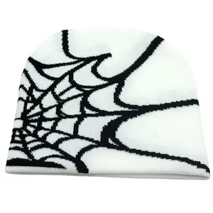 Detailed close-up showing black spider web jacquard pattern on a white knit beanie