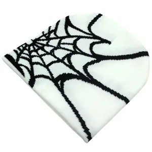 Close-up of white knitted beanie with black spider web pattern and soft texture