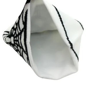 Close-up of white knitted beanie featuring black spider web jacquard and thick double-layer fabric