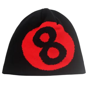 Détail du tissage et du motif jacquard boule 8 rouge sur un bonnet en maille noir
