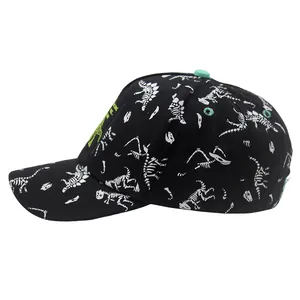 Detail view of cotton baseball cap with dinosaur skeleton print and green embroidery