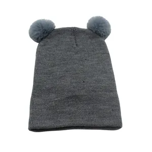 Macro-opname van grijze gebreide baby wintermuts met twee zachte pompons van imitatiebont