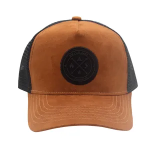 Detail of the circular embroidered patch on brown suede trucker hat with mesh back