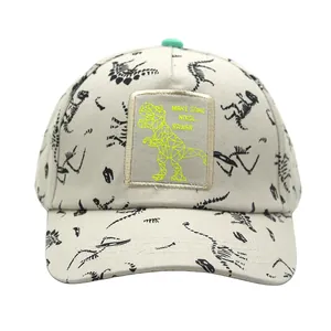 Close-up of beige kids baseball cap with dinosaur skeleton prints and green patch